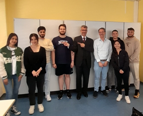 Schülerinnen und Schüler posieren gemeinsam mit dem leitenden Sachverständigen der Europäischen Kommission, Ulrich Trautmann im Klassenzimmer.